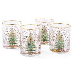 four glasses with christmas trees on them are sitting next to each other and have gold rims