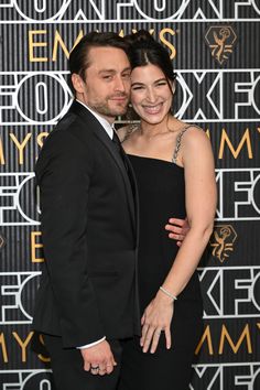 a man and woman standing next to each other on a red carpet