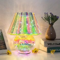 a colorful lamp sitting on top of a table next to a vase with flowers in it