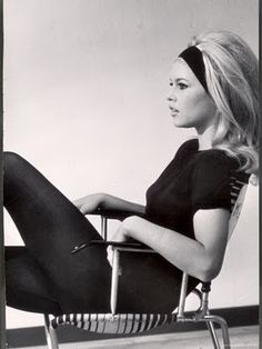 a black and white photo of a woman sitting in a chair with her legs crossed