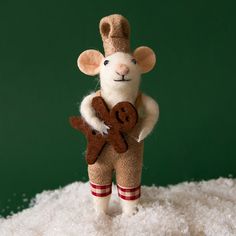 a toy mouse holding a gingerbread cookie in its hand on top of some snow