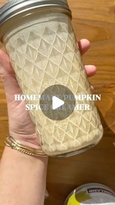 a person holding a mason jar over a wooden table