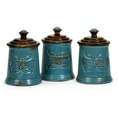 three teal ceramic canisters with metal lids and designs on the top, one has a brown lid