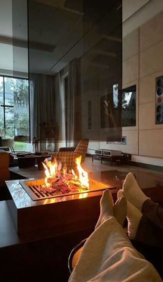 a person sitting in front of a fire pit with their feet up on the table