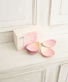 three pink plates sitting on top of a white counter next to a box with the lid open