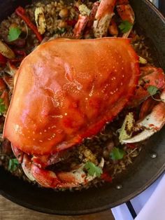 a large cooked crab in a skillet with rice and garnishes