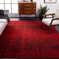 a living room with a red rug on the floor and furniture in front of it