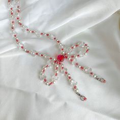 a red and white beaded necklace is laying on a white bed sheet with beads