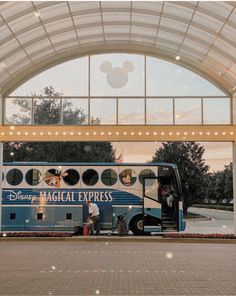 a bus parked in front of a building with mickey mouse on it's side