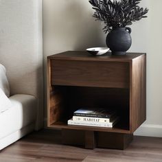 a wooden table with a vase and books on it next to a couch in a living room