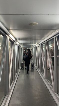 a person walking down a long hallway with luggage