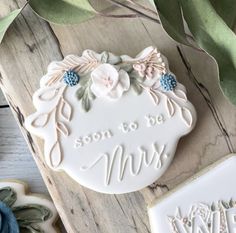 some cookies that are on top of a wooden table with leaves and flowers around them