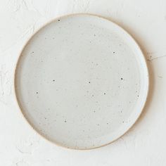 a white plate with speckles on it sitting on a table next to a wall