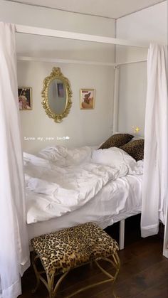 a bed with white sheets and leopard print foot stool