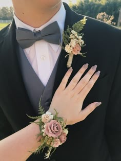 a close up of a person wearing a suit and tie with flowers on his wrist