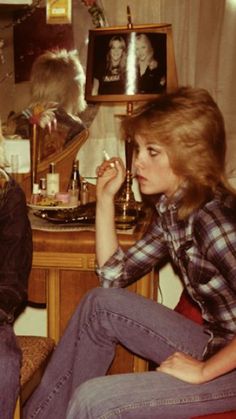 two women sitting on the floor in front of a table with makeup and hairbrushes