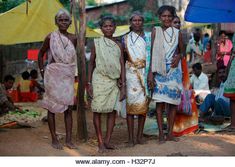 three women standing next to each other in front of a group of people with umbrellas