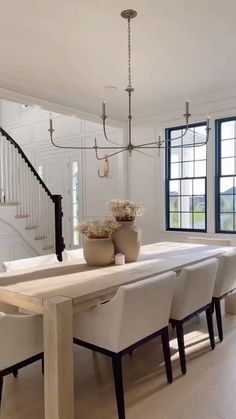 a dining room table with white chairs and a chandelier hanging from the ceiling