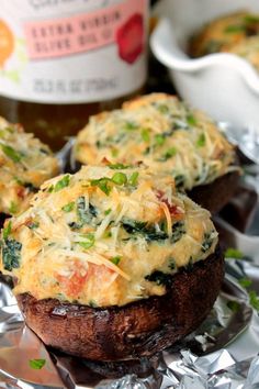 three stuffed mushrooms with cheese and vegetables on them sitting on tin foil next to ketchup bottles