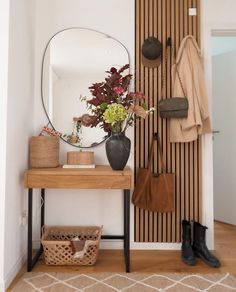 an entryway with a mirror, coat rack and purses on the shelf next to it