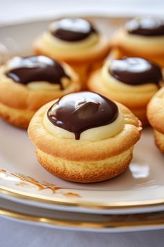 some chocolate covered cookies on a plate with gold trimmings and white frosting