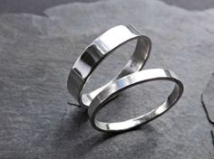 two silver rings sitting on top of a rock