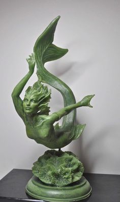 a statue of a mermaid holding a plant