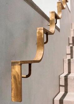 some metal brackets on the side of a wall next to stairs and cement steps with white walls