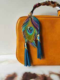 an orange purse with blue tassels and a peacock decoration hanging from the handle