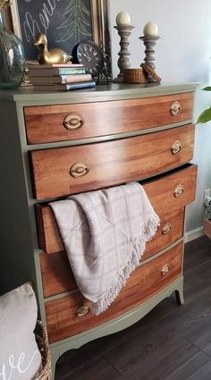 a wooden dresser with a chalkboard on the wall above it and a towel hanging from the drawer