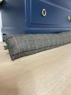 a pillow sitting on top of a wooden table next to a blue cabinet and drawers