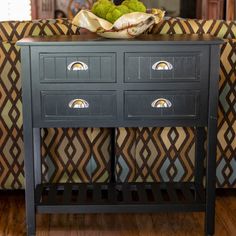 a black cabinet with drawers sitting on top of a wooden floor next to a couch