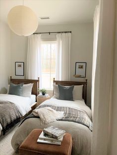 two beds in a bedroom with white curtains