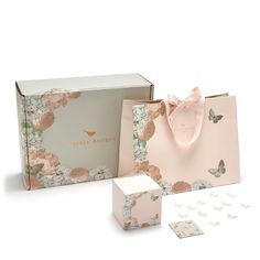 a pink gift bag and two matching boxes with butterflies on them, one is open to reveal the contents