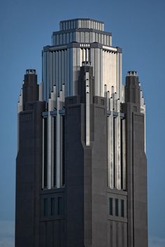 the top of a tall building with many windows on it's sides, against a blue sky