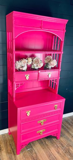 a pink china cabinet with cupcakes on top and flowers in the bottom drawer