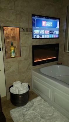 a bathroom with a fireplace and tv above the bathtub