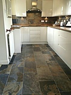 a kitchen with white cabinets and black slate tile flooring in it's center