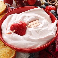 a red bowl filled with whipped cream surrounded by fruit