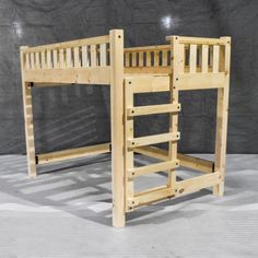 a wooden bunk bed sitting on top of a white floor next to a gray wall