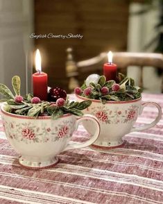 two tea cups with candles in them sitting on a table