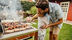 a father and son grilling meat on a bbq in the back yard,