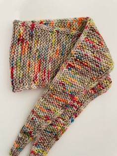 two knitted gloves laying on top of each other in different colors and patterns, with one folded up to the side