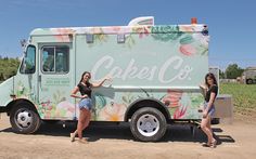 two women standing in front of a food truck with flowers painted on it's side