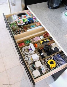 an open drawer in the middle of a kitchen counter with various items on it and other things inside