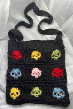 a black crocheted bag with skulls on the front and multicolored eyes