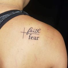 a woman with a cross tattoo on her upper arm and the word faith is written in cursive font