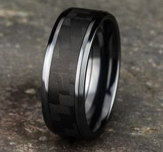 a black and white wedding ring with an arrow pattern inlayed to it's center