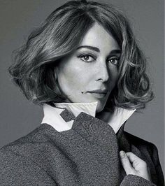 a woman is posing for a black and white photo with her necktie pulled back