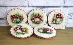 four ceramic plates with mushrooms on them sitting on a table next to a brick wall